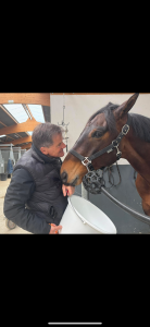 Éric partage un moment de confiance avec un cheval dans une écurie, illustrant l’attention, le respect et le lien dans la relation homme-cheval.